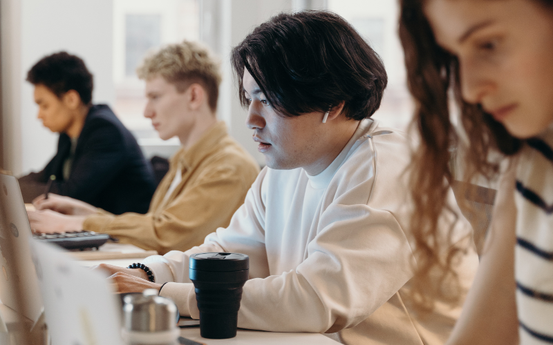 Four people sitting working on laptops