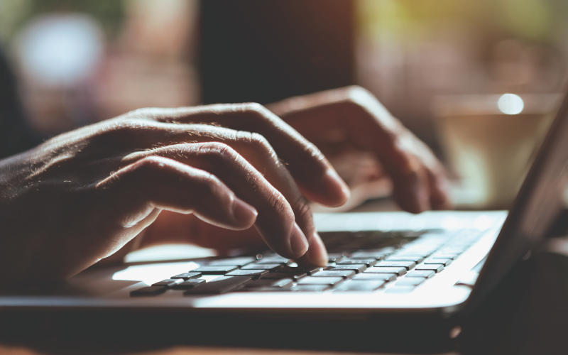 Photograph of hands at a laptop keyboard