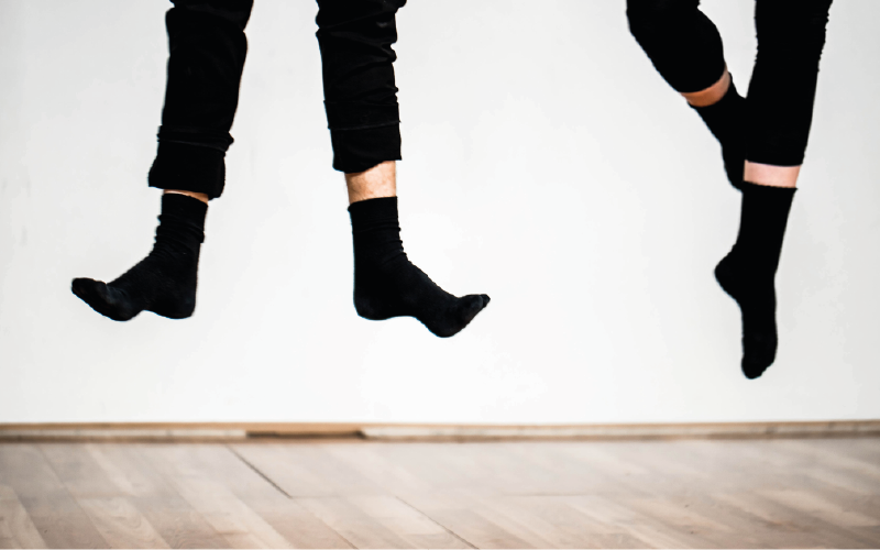 Photograph of two pairs of feet, male, in mid-air, dancing