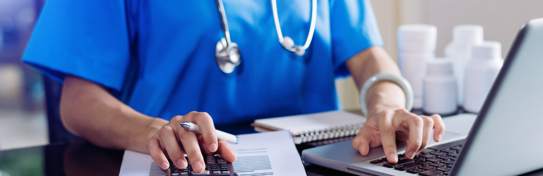 a picture of a doctor working at a laptop