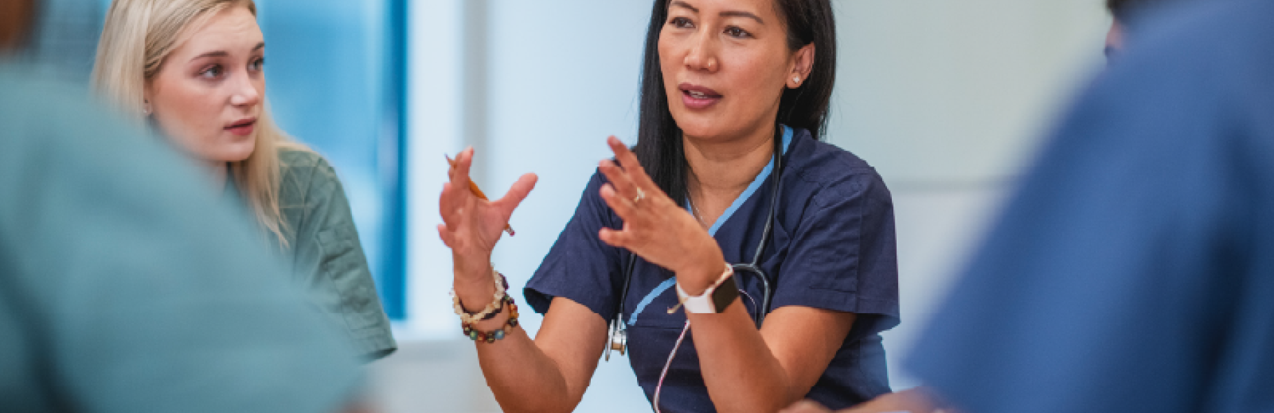 Group of health professionals sat round a table in a meeting