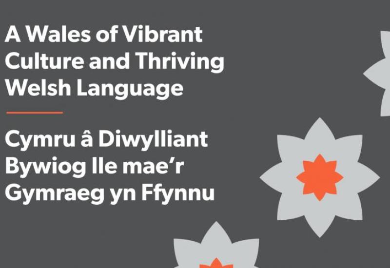 Page title wording with a stylised daffodil in Audit Wales corporate colours of white and orange on a grey background